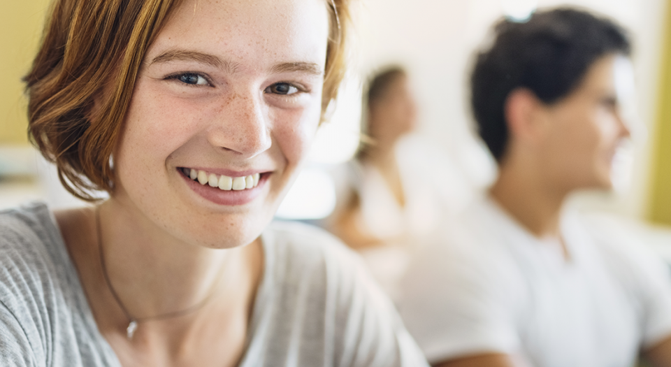 Une jeune femme assise dans une classe sourit